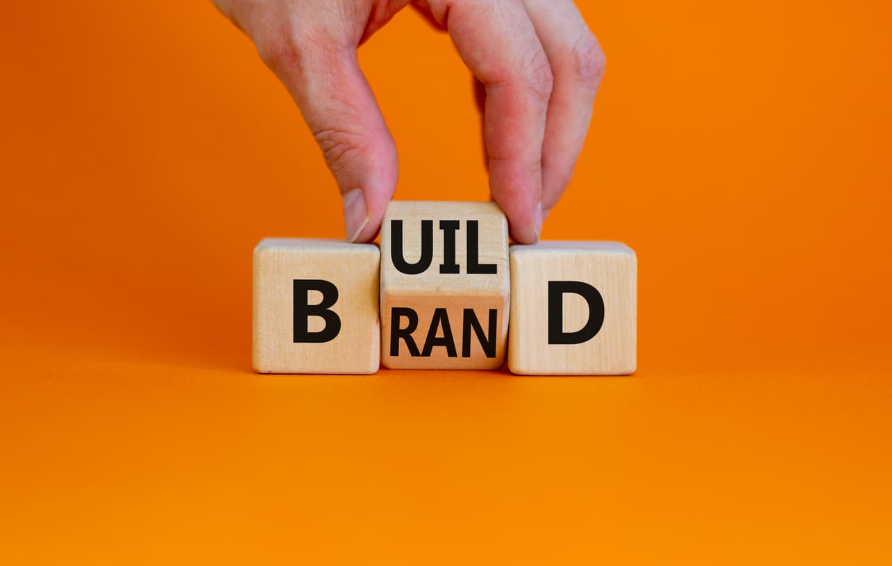 hand moving blocks spelling out build brand with orange background